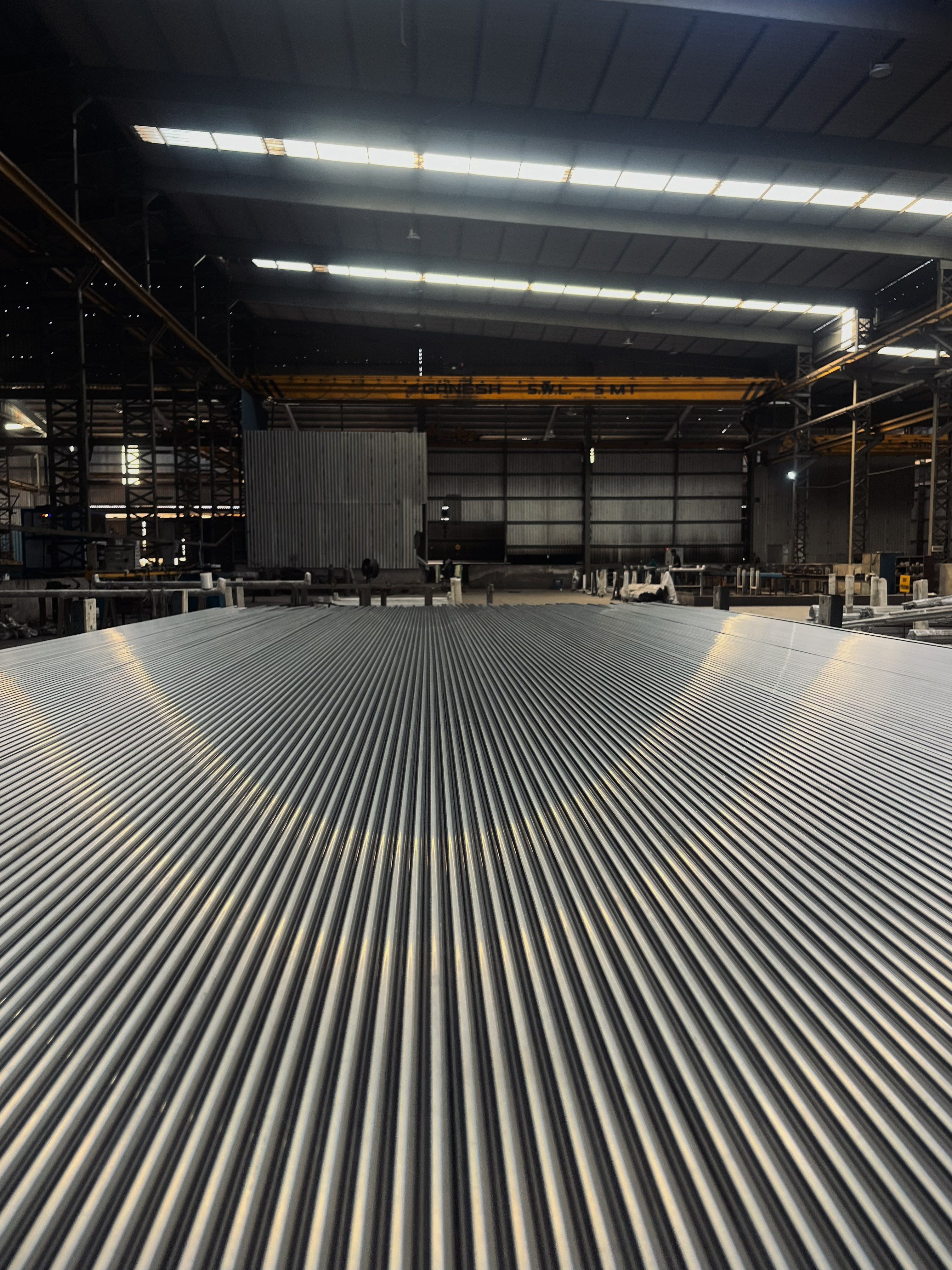 Rows of polished stainless steel pipes stretching across the factory floor